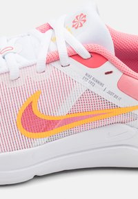 Scarpa da corsa Nike con tomaia a strisce bianche e rosa, logo swoosh arancione vivace, texture in rete e suola bianca. Caratterizzata da design con lacci e logo.