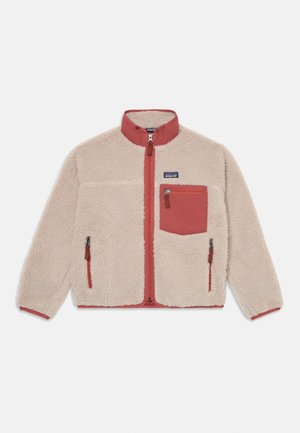 Veste en polaire beige clair avec un col montant, fermeture éclair à l'avant et une poche rouge en contraste. Comprend des poches latérales à fermeture éclair et un tissu texturé.