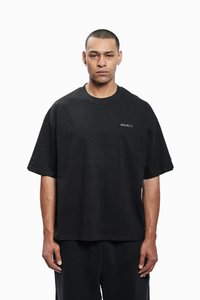 T-shirt noir oversize en coton, avec un col rond et des manches courtes, portant "FAVELA" brodé sur la poitrine en blanc.