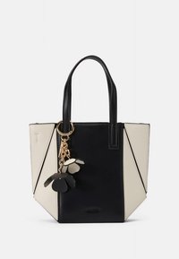 Black and cream tote bag featuring geometric design, leather material, top handles, and a floral charm attached.