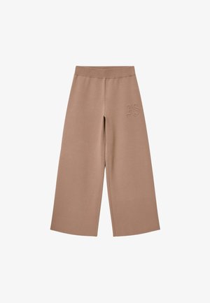 Beige wijde broek met een gestructureerde afwerking, voorzien van een zachte elastische tailleband en een "AS" geborduurd detail op de linkerheup.