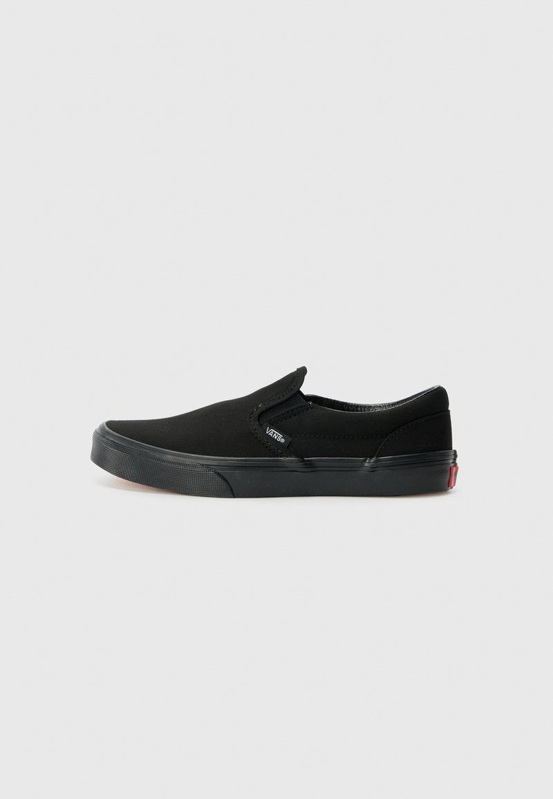 Bottines en toile noires à enfiler avec une semelle en caoutchouc plate, des accents élastiques sur les côtés et une petite étiquette logo sur le côté. Design et texture minimalistes.