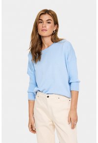Maglione azzurro chiaro in maglia con una vestibilità comoda, ampi polsini a coste e scollatura rotonda, abbinato a pantaloni color crema.