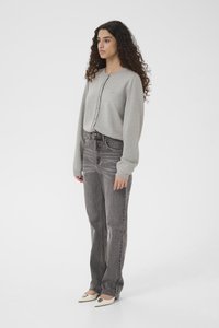 Grey cotton sweatshirt with button closure, paired with straight-leg gray jeans. Footwear includes white heels with a decorative accent.