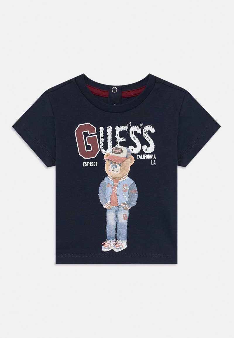 Marineblauwe katoenen t-shirt met een beerafbeelding in een spijkeroutfit, met rode accenten en de tekst "GUESS CALIFORNIA L.A. EST. 1981."