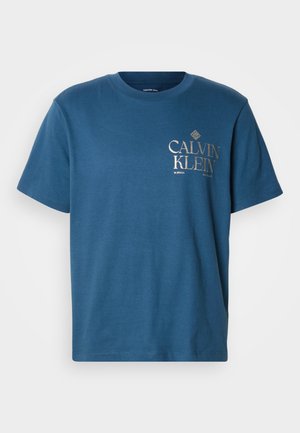 Modré bavlnené tričko s krátkymi rukávmi. Na prednej strane je zlaté logo "CALVIN KLEIN". Klasický dizajn s okrúhlym výstrihom, hladká textúra.