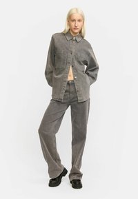 Grijze denim shirt met een puntige kraag, twee borstzakken en een knopenfront. Gecombineerd met bijpassende grijze wijde jeans en chunky zwarte laarzen.