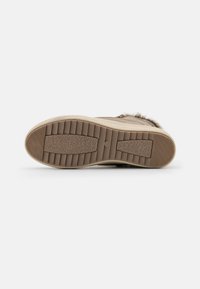 Chaussures brunes avec une semelle en caoutchouc texturé, présentant des rainures verticales et une légère élévation. Accents en fourrure douce le long du bord supérieur.