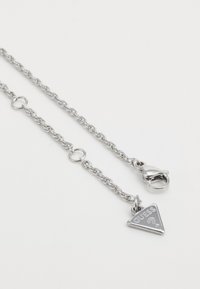 Colier din argint cu pandantiv triangular gravat cu "GUESS?" și închidere cu carabină. Design cu verigi texturate.
