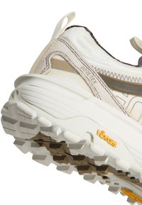 Gros plan sur le talon d'une basket Gore-Tex blanche et beige avec une semelle Vibram texturée conçue pour la traction et la durabilité.