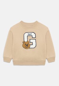 Felpa beige con scollo rotondo. Presenta un orso ricamato e la lettera "G" con il testo "GAP" in blu navy. Tessuto morbido, polsini a coste.