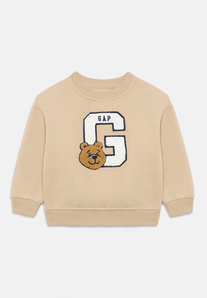 Felpa beige con scollo rotondo. Presenta un orso ricamato e la lettera "G" con il testo "GAP" in blu navy. Tessuto morbido, polsini a coste.