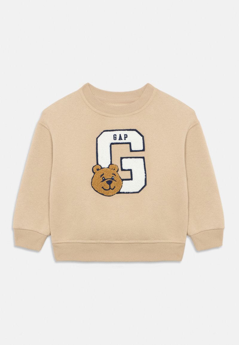 Felpa beige con scollo rotondo. Presenta un orso ricamato e la lettera "G" con il testo "GAP" in blu navy. Tessuto morbido, polsini a coste.