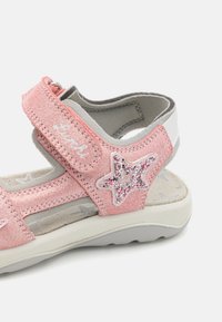 Vaaleanpunaiset taaperon sandaalit, joissa on kangasosa, tarranauha, harmaat yksityiskohdat ja kimaltava tähtipatchi. Taipuisat pohjat, joissa on kuviollinen sisäpohja.