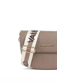 Beige Ledertasche mit geprägt-eingsprägtem Logo-Muster, goldenen Beschlägen und einem gestreiften Stoffriemen mit dem Markennamen in Schwarz.