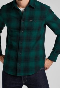 Groen en zwart geruit flanellen shirt, met knopen, lange mouwen, enkele borstzak, zachte textuur, gebogen zoom.