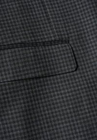 Grått mönstrat tyg med ett subtilt rutmönster. Har en kantficka med en ren finish och texturerad yta.