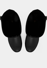 Czarne gumowe klompy o gładkiej fakturze, zaokrąglonym kształcie i otwartym tyle. Wnętrze jest ciemne z minimalnymi detalami. Lekka konstrukcja.