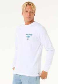 Langærmet hvid bomulds t-shirt med turkise grafikker på brystet, rund hals og lige kant. Klassisk pasform.