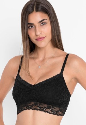 Bralette in pizzo nero con un motivo floreale, spalline regolabili e un bordo in pizzo scallopato nella parte inferiore. Tessuto morbido e leggero.