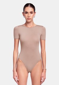 Body in tinta nude con maniche corte e scollatura rotonda. Presenta un design morbido e aderente con aperture alte sulle gambe. Texture del tessuto morbida.