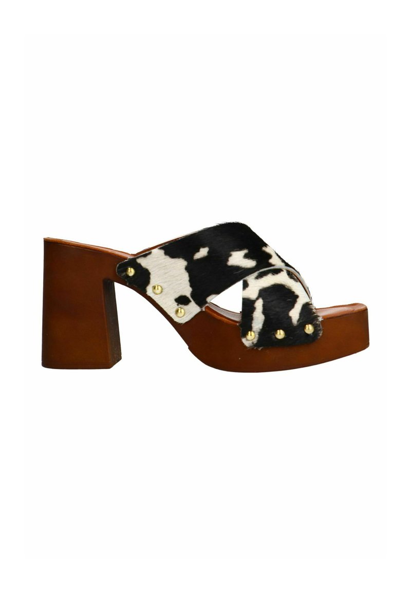Block-heeled clogs with a brown leather base and a black and white cow print fur strap, accented with gold studs on the side.