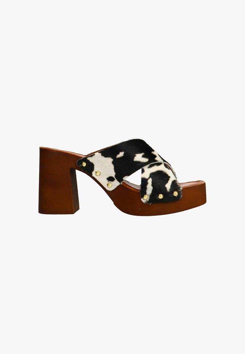 Block-heeled clogs with a brown leather base and a black and white cow print fur strap, accented with gold studs on the side.