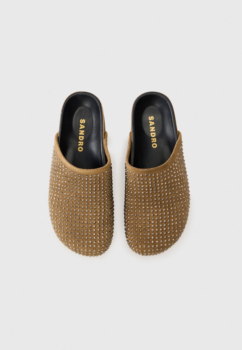 Braune Wildleder-Slipper mit Nietenverzierung an der Oberseite, schwarzem Innenfutter und geprägt Logo auf der Innensohle.