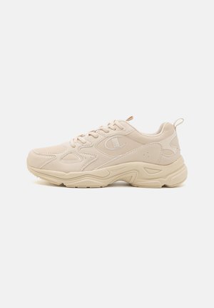 Beige chunky sneaker med snørelukning foran, tyk sål og et syet logo på siden, vist fra ydersiden på hvid baggrund.