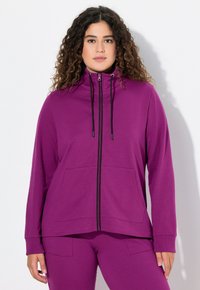 Fialová mikina na zip s předním zipem, vysokým límcem a dvěma předními kapsami; vyrobena z měkké tkaniny, s dlouhými rukávy a elastickými manžetami.