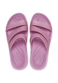 Roze slide sandalen met drie glinsterende banden, zacht binnenmateriaal en een glanzende afwerking op de zool. Crocs-logo zichtbaar op de voetbed.