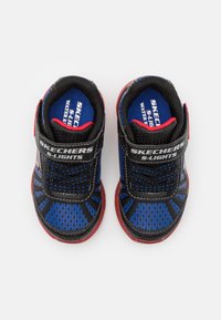 Para niebiesko-czarnych butów sportowych Skechers S-Lights dla dzieci z czerwonymi akcentami i rzepami na białym tle.