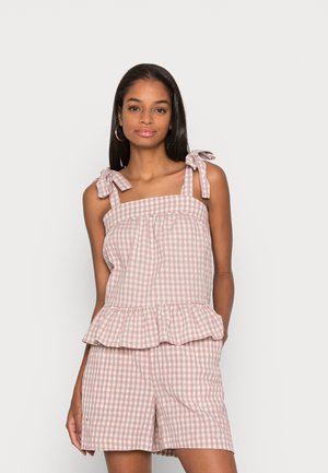 Top peplum em ganga rosa e branca com alças de ombro e calções a condizer, apresentando um tecido de algodão texturizado e uma bainha com volantes.