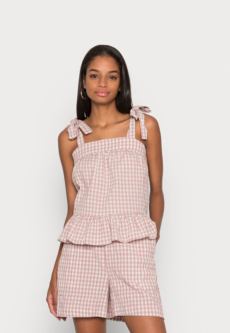 Top peplum em ganga rosa e branca com alças de ombro e calções a condizer, apresentando um tecido de algodão texturizado e uma bainha com volantes.