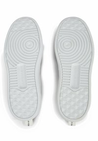 Suole di scarpe in gomma bianca con motivi testurizzati, scanalature circolari e un logo impresso sul lato. Design leggero e flessibile.
