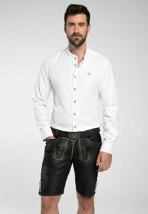 Weißes Hemd mit Stehkragen, kombiniert mit schwarzen Leder-Shorts mit gelben Ziernähten und dekorativen Akzenten.