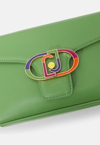 Clutch de cuero verde con cierre de solapa, que presenta un broche rectangular colorido en rosa, morado y naranja. Textura suave, diseño minimalista.