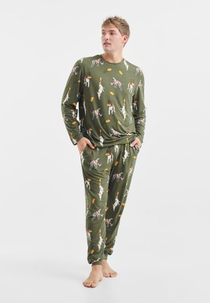 Grünes Langarm-Pyjama-Set mit verspielten Hundemustern und gelben Akzenten, aus weichem Material, mit lockerer Passform und seitlichen Taschen.