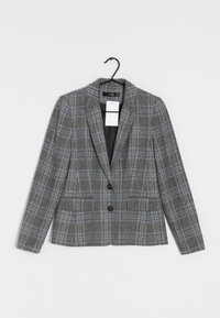 Szary blezer w kratę o strukturalnym wzornictwie. Posiada klapę w kształcie litery notched, dwa guziki oraz dwie przednie kieszenie. Wisi na czarnym wieszaku.