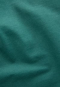 Tela de algodón color verde azulado con una textura suave, que presenta sutiles ondulaciones y un fino acanalado que captura la luz en diferentes tonos de verde.