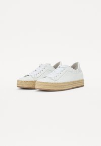 Sneakers in pelle bianca con suola piatta in tessuto beige intrecciato, dotate di lacci piatti e dettagli laterali minimalisti.