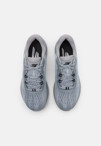 Baskets de sport grises avec une tige en mesh, surface texturée, lacets noirs et une semelle rembourrée. Présente un logo sur le côté et un col rembourré.