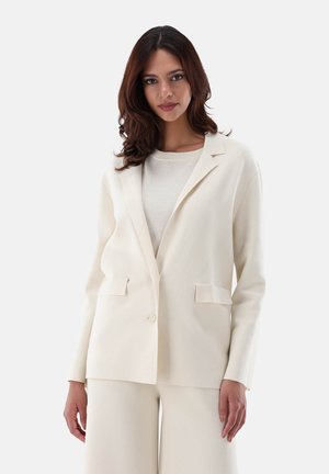 Cremefarbener Blazer mit Reverskragen, Ein-Knopf-Verschluss und zwei Fronttaschen. Glatte Textur, taillierter Schnitt, kombiniert mit einem leichten Oberteil.