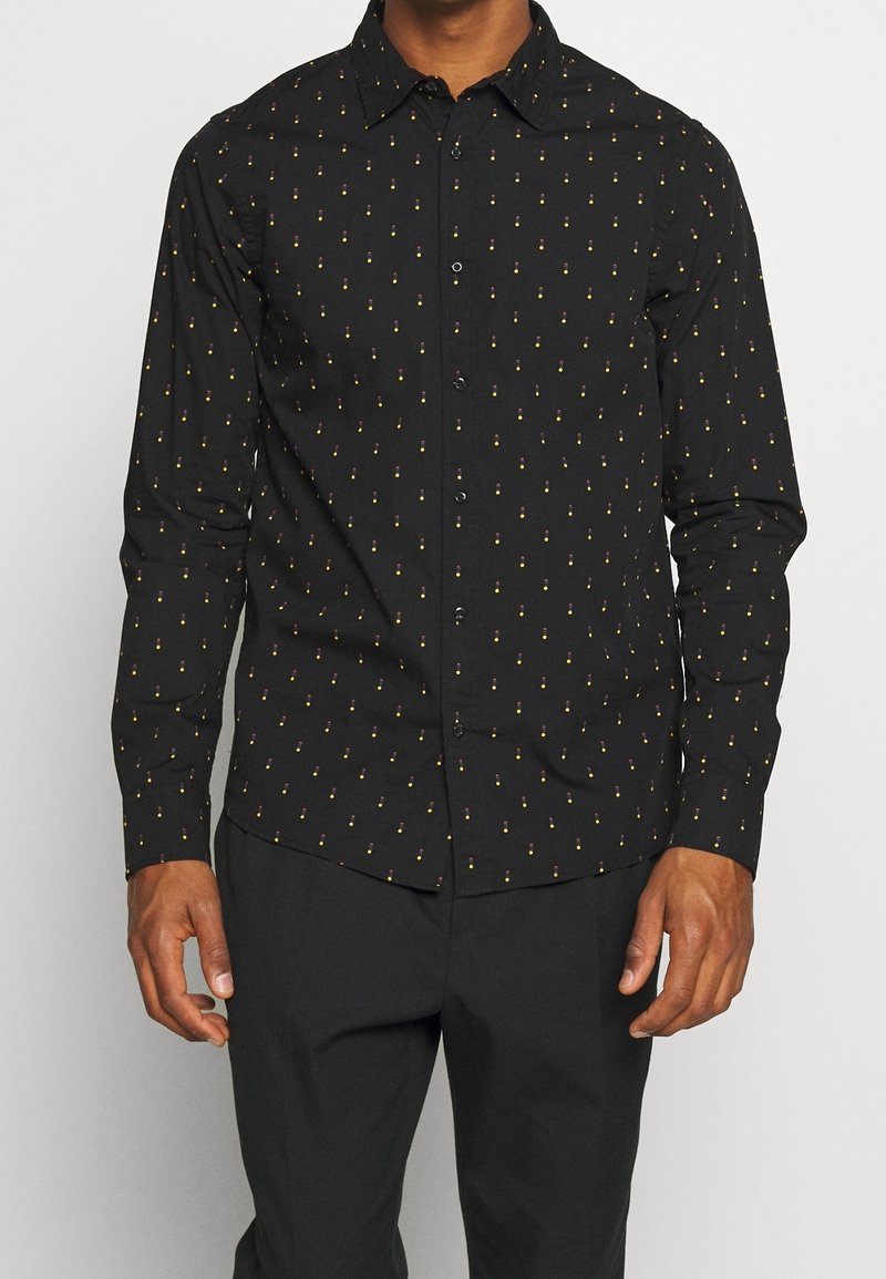 Camisa negra de botones con un sutil patrón amarillo y rojo. Mangas largas, cuello clásico y una textura suave. Ajuste entallado.