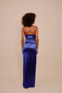 Satynowa wieczorowa suknia w intensywnym niebieskim kolorze. Bez ramiączek, o dopasowanym kroju, z delikatnym marszczeniem i zamkiem z tyłu.