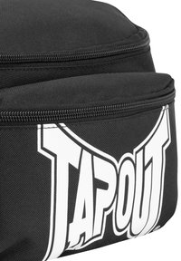 Borsa in tessuto nero con texture liscia, caratterizzata da un prominente logo bianco "TAPOUT" sul davanti e scomparti con zip per il riposo.