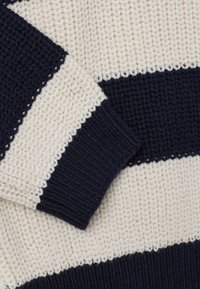 Jersey de punto con rayas alternas en crema y marino, puños acanalados y un patrón texturizado y tejido en toda la prenda.
