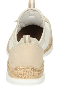 Beige sneaker with a rounded shape, soft upper material, textured cork sole, and a fabric heel tab with striped accents.