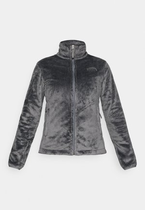 Casaco de fleece cinza com gola alta, fecho frontal, bolsos laterais e logotipo no lado esquerdo do peito. Textura suave e design ajustado.