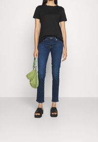 Black short-sleeve t-shirt, blue denim jeans, black platform sandals, and a green suede shoulder bag. Simple, casual outfit.
